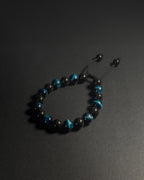 Black and blue beaded bracelet on a dark surface. Black beaded bracelet with blue tiger eye 