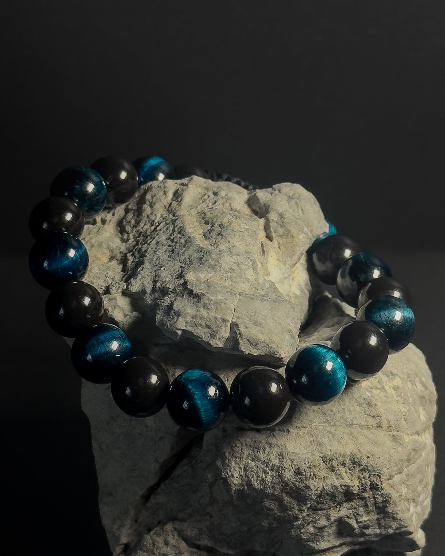 Blue and black beaded bracelet on a rock with a dark background