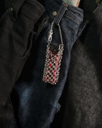 A close-up of a stainless steel chainmail sleeve with lighter, hanging from the waistband of dark blue denim jeans.