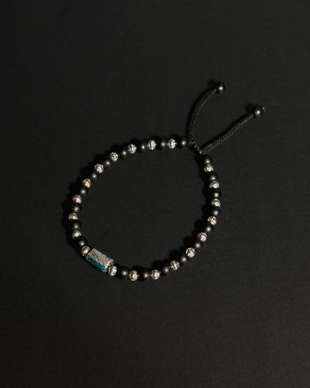 Product image of an adjustable bracelet featuring apatite and matte black onyx against dark background.