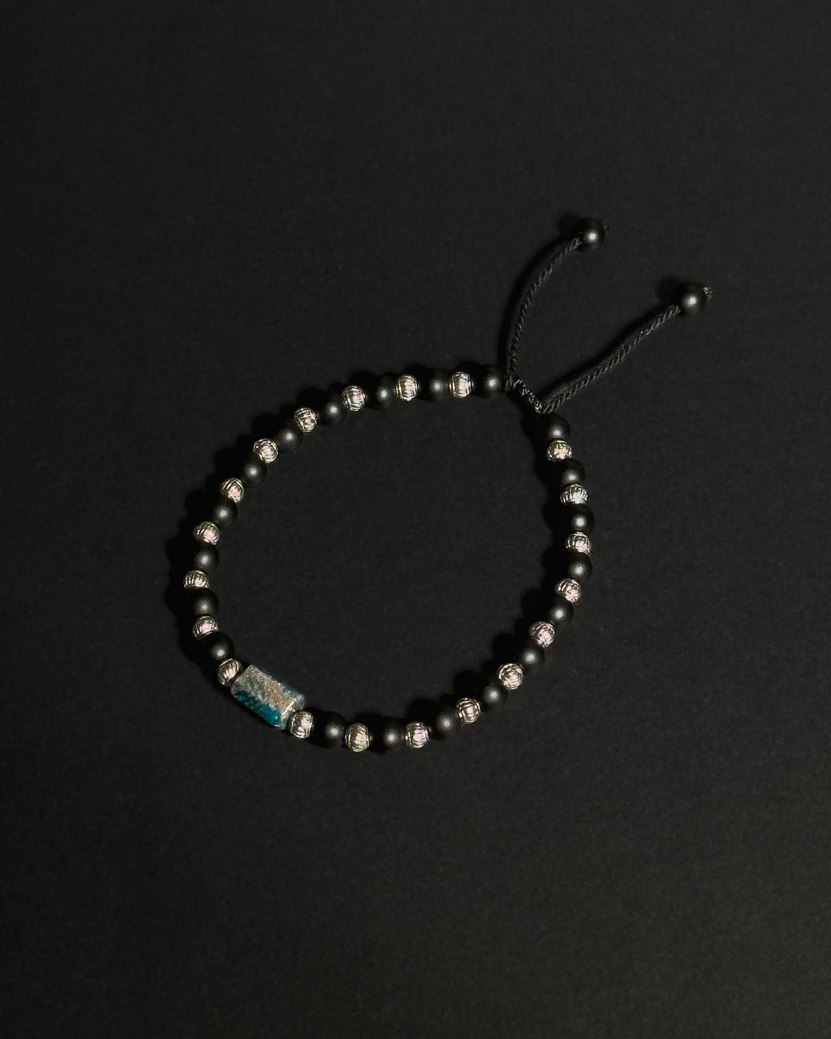 Product image of an adjustable bracelet featuring apatite and matte black onyx against dark background.