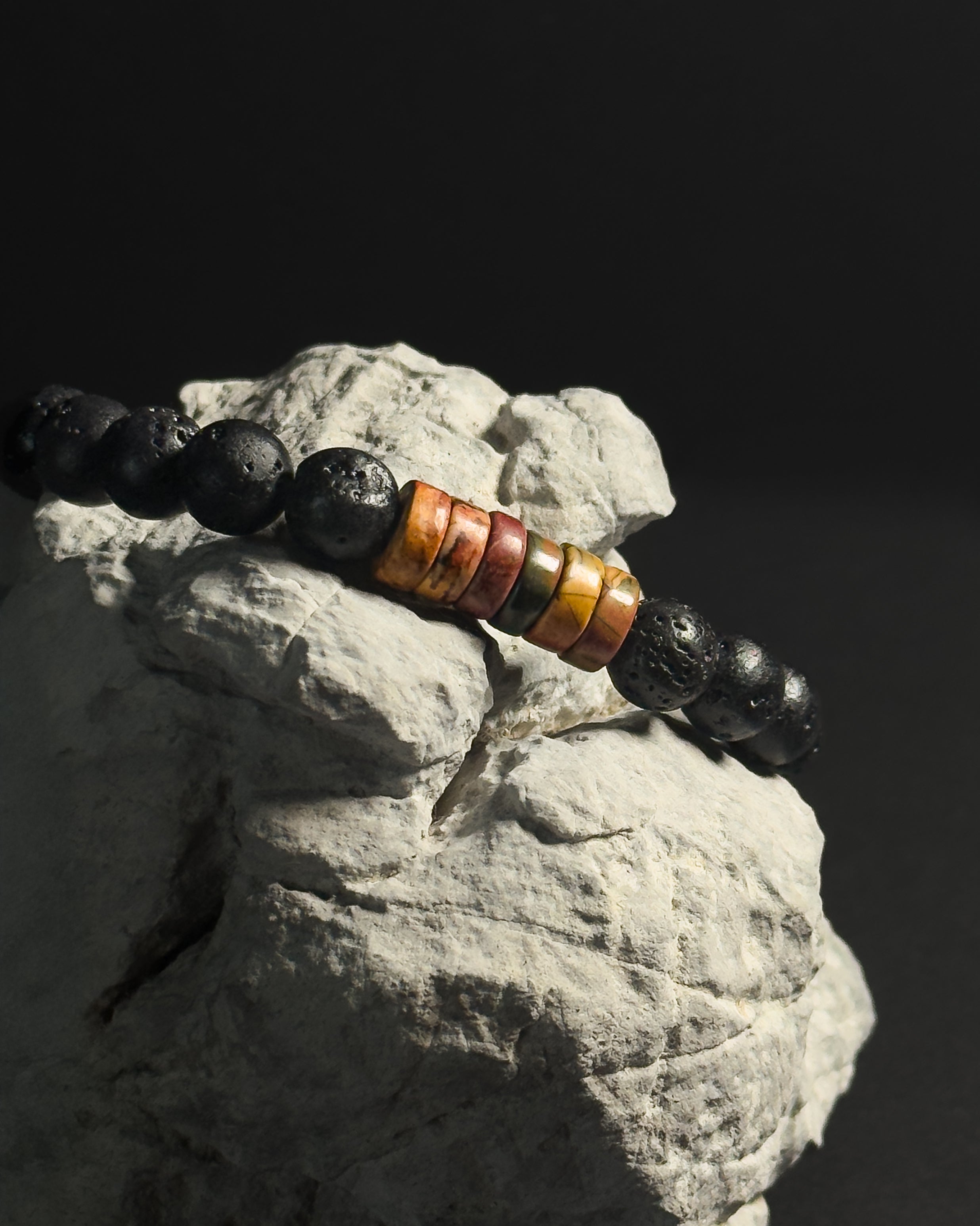 Handcrafted adjustable Picasso jasper and lava stone bracelet styled on a natural rock.