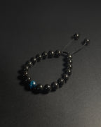 Black beaded bracelet with a blue accent bead on a dark background