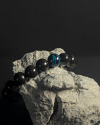 Black and blue beaded bracelet on a rock with a dark background