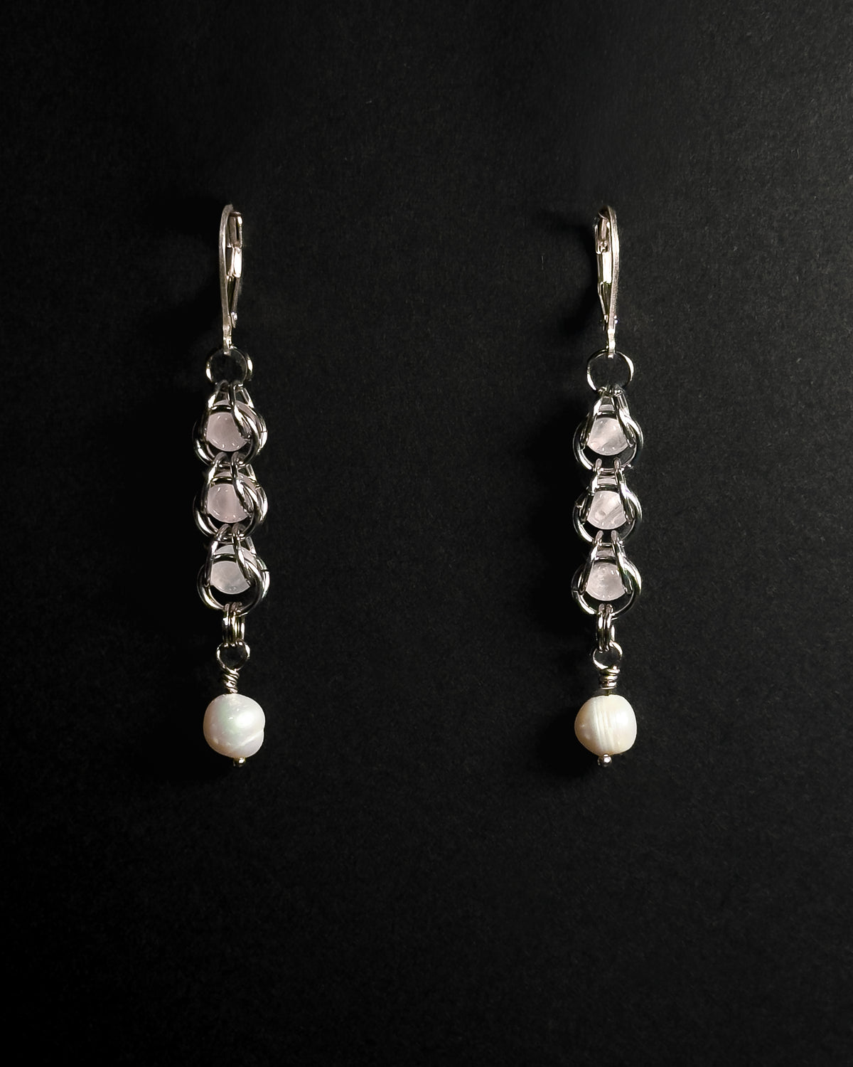 Natural Rose Quartz capture bead earrings with lever back hooks with freshwater pearl against dark background