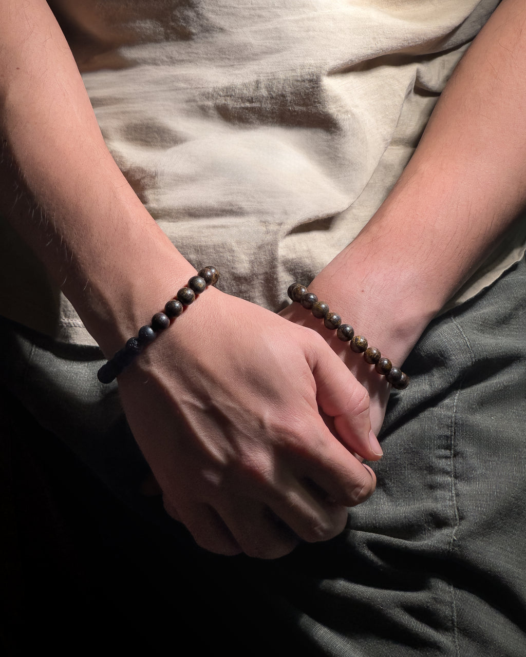 Model wearing handmade Trailborn and Earthbound Bracelet featuring 8mm bronzite and lava stone beads with adjustable sliding knot closure.