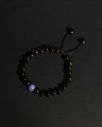 A beaded bracelet made of tourmaline with a single sodalite, shown on a dark background.