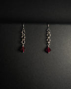 Stainless Steel hooked dangle earrings made with jumprings link by link with a geometric garnet against dark background.