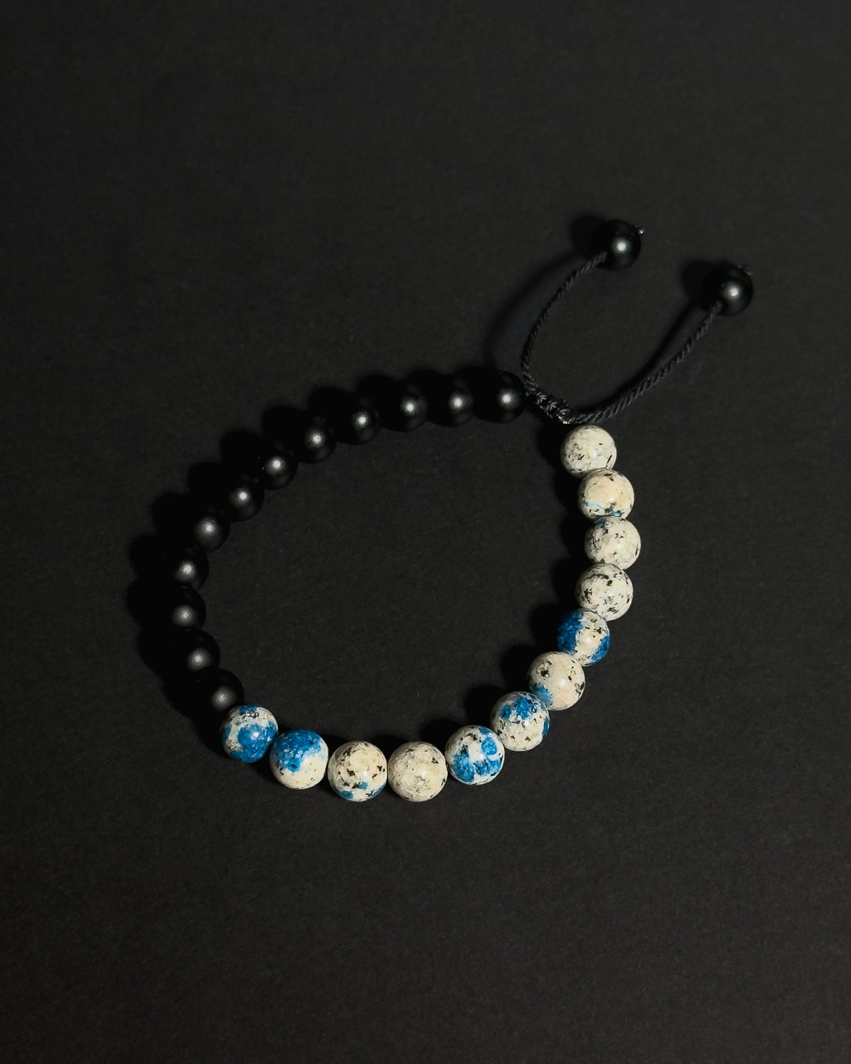 Handmade natural K2 and Matte Black Onyx adjustable bracelet aainst dark background.