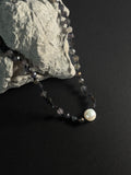 Necklace with beads and a pearl on a dark surface