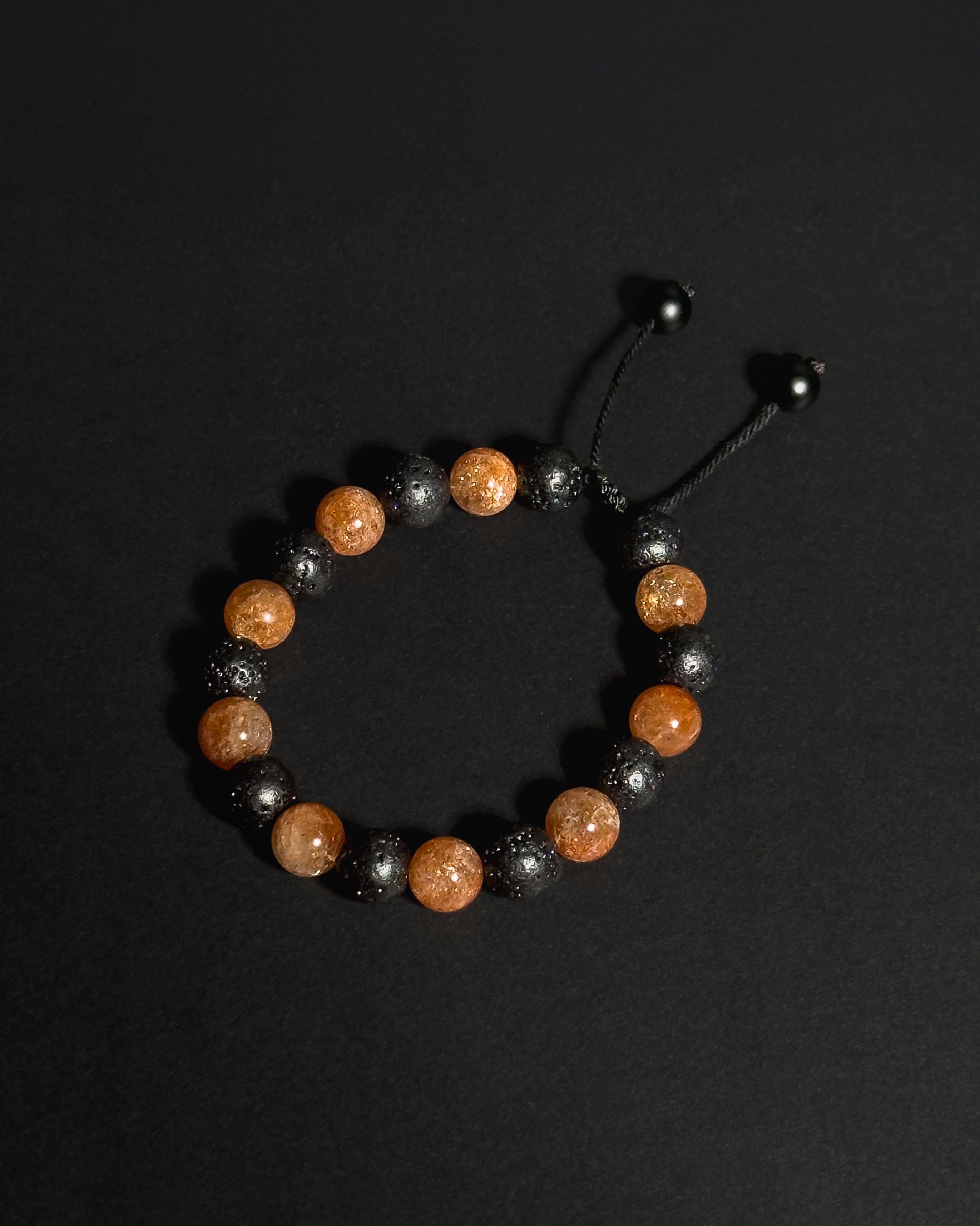 Close-up of natural 10mm sunstone and lava stone beads alternating, showing unique stone textures and variations.