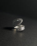 Solid stainless steel spoon ring with a textured, stud-like in a wrap finish, shown open on a dark surface.