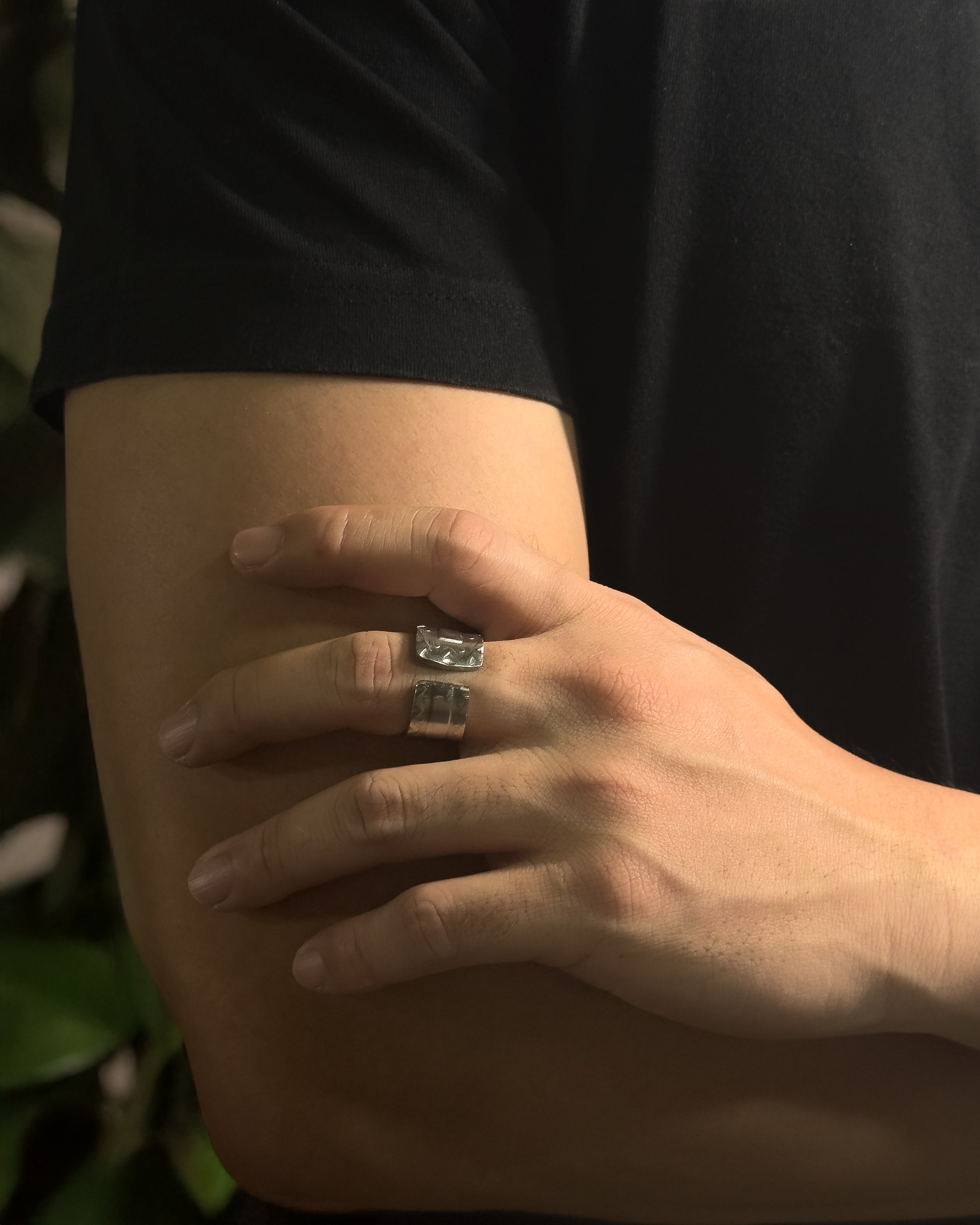 A close-up of a person's hand resting on their arm, wearing a Solid stainless steel spoon ring in black t-shirt and leafy background