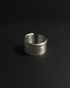 Solid stainless steel spoon ring displayed on a dark, matte black surface.