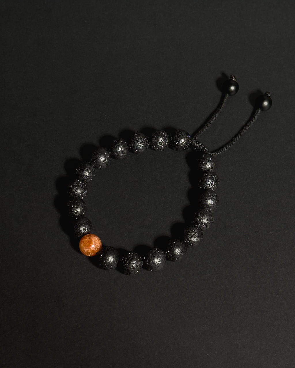 Close-up of natural 10mm sunstone and lava stone beads on The Rising Sun Bracelet showing unique stone textures and variations.