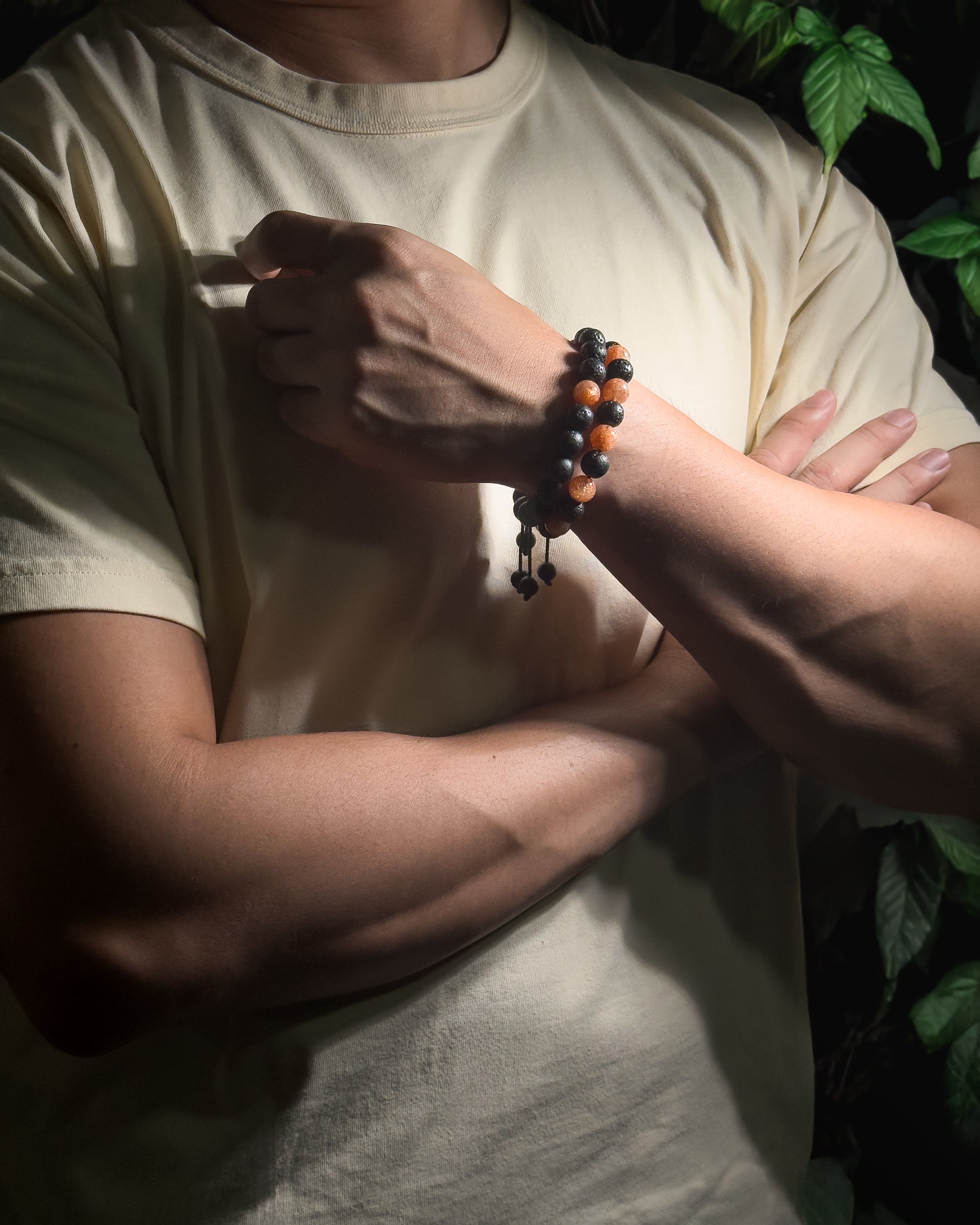 Model wearing the Sunkeeper Bracelet featuring a single sunstone centre bead surrounded by natural lava stone beads, handmade with unique variations.