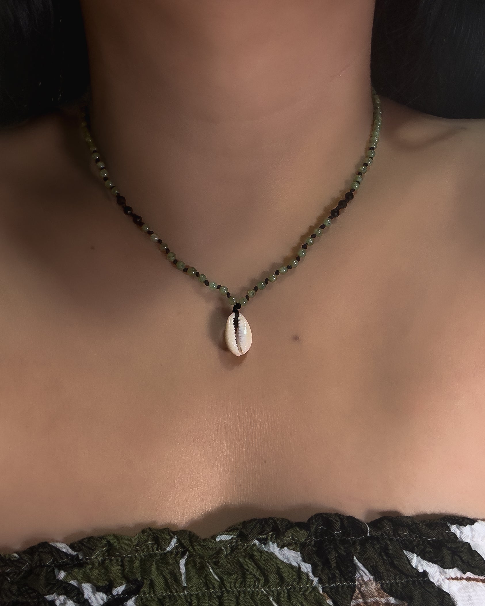 Beaded Necklace with a shell pendant worn by a person