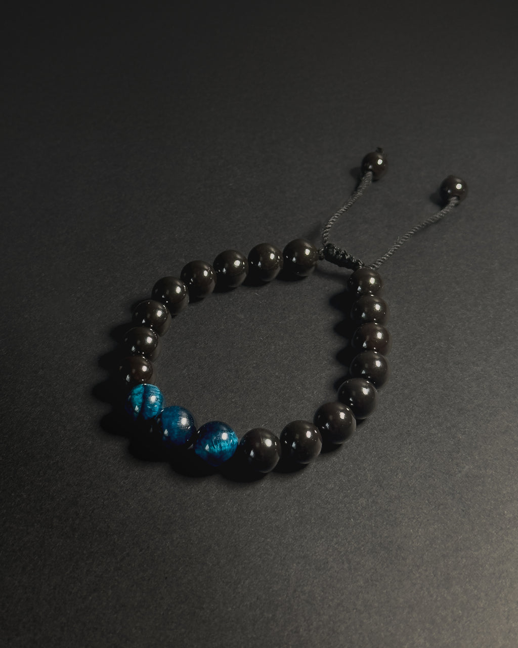Black beaded bracelet with blue accents on a dark background